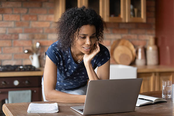 Young woman using laptop looking interested and engaged
