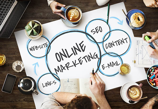 Overhead view of desk with digital marketing terms written on large piece of paper and cups of coffee