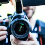 Close up of man with video camera. You are looking straight into the lens.