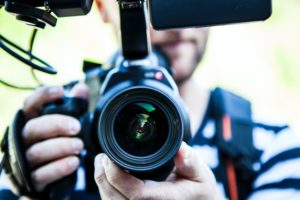 Close up of man with video camera. You are looking straight into the lens.